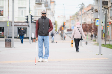 Blind african american man standing with stick on city street