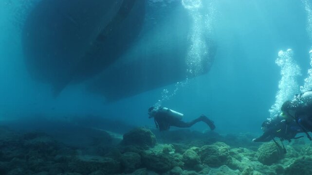scuba diver scenery under the parked boats with sun beams and rays underwater