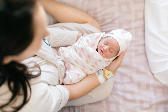 Newborn baby being held by mom overhead shot pink