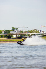 Fototapeta premium Rider Executing Swift Turns On Waterway. Watercraft Slicing Through River With Spray In Urban Setting