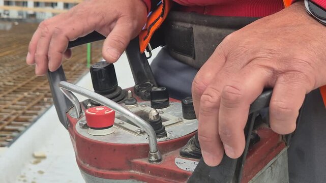 Close up video of an operator holding and controlling a concrete pump with a wireless remote control console in normal speed.