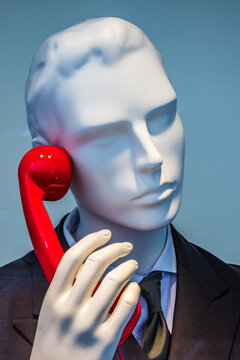 Mannequin holding a yellow phone in a retail store during a busy shopping day in the city center
