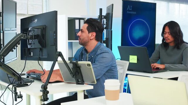 Two focused software engineers collaborating on code in modern office, professional developers discussing project on laptop and computer screen