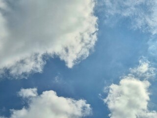 Obraz premium Bright Blue Sky with Soft White Clouds Creating Peaceful Natural Weather Background