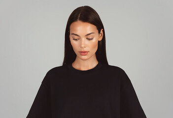Fototapeta premium Young Woman Looking Down in Plain Oversized Black T Shirt for Minimal Studio Fashion Mockup