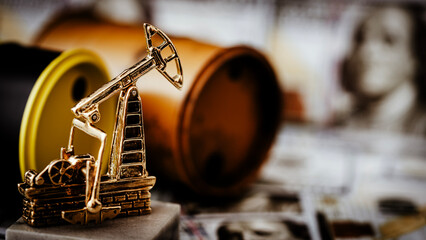 Golden oil pump stands beside barrels © I
