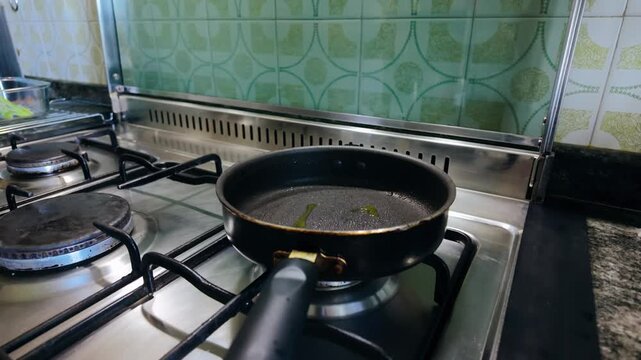 Woman's hands pouring a beaten egg mixture into a hot frying pan on a gas stove, preparing a delicious and healthy homemade meal with fresh ingredients for a nutritious breakfast