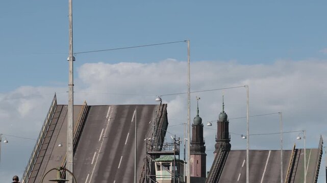 Stockholm, Sweden Two road sections of the Liljeholmsbron bascule Bridge falling back into place after raising to let a boat pass, and the Hogalid Church. 