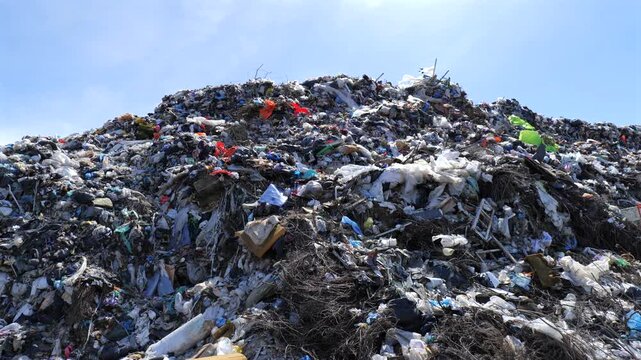 Large landfill area is filled with mixed trash and waste, highlighting pollution and its impact on the environment in this location