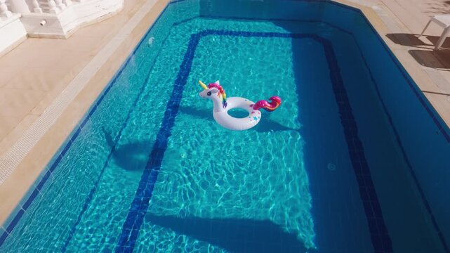Summer fun with a unicorn float in a blue swimming pool during a sunny day