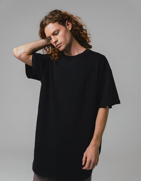 Man with Long Curly Hair Wearing Plain Black Longline T Shirt in Relaxed Studio Pose