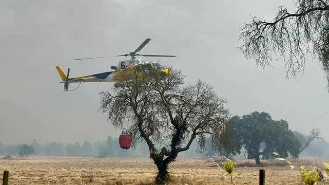 Helic&oacute;ptero de lucha contraincendios despegando con bambi naranja enganchado para cargar agua