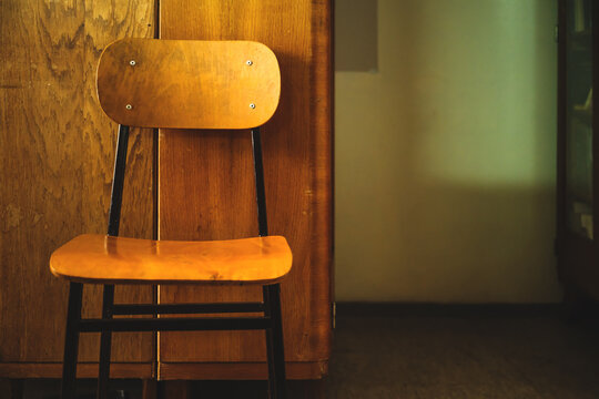 Vintage wooden school chair leaning against old wooden cabinet