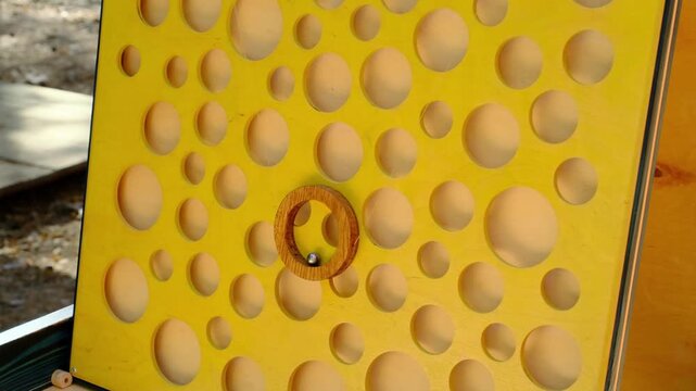 A children's educational board game featuring mice and cheese on a vertical wooden board with a metal ball in a ring. Board games. Horizontal video