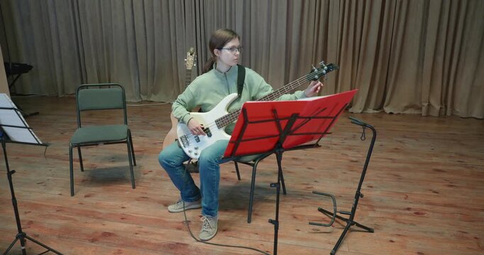 Boy and Girl Practice Playing Music on Stage. Kids Play Guitar and Bass Guitar. 4K 10-bit