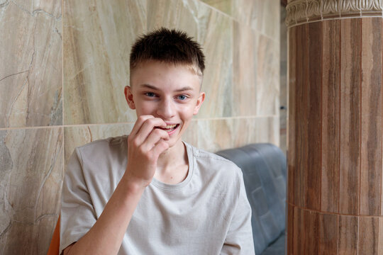 Cheerful teenage boy laughing with hand near mouth indoors, candid joyful youth lifestyle portrait concept
