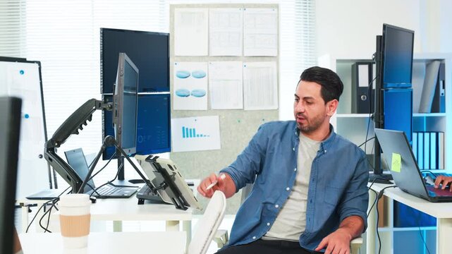 Two focused software engineers collaborating on code in modern office, professional developers discussing project on laptop and computer screen