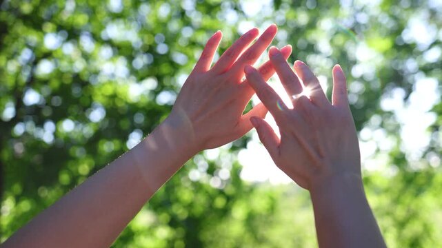 Female hand reaches out to sun at sunset. Sun rays shine through fingers of woman. Enjoying warm summer evening outdoors. Unity with nature. Silhouette arm in sun. Religion lends helping hand.