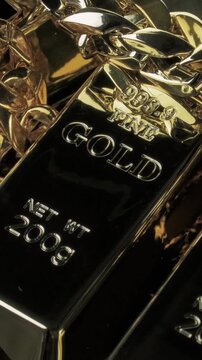 Portrait 9:16 Full HD stock video featuring rotating gold bullion bars and a chunky gold chain, ideal for themes of wealth, prosperity, investment security, luxury lifestyle and value