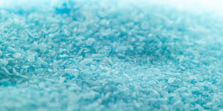 Close-up view of blue salt crystals on a flat surface in a bright light