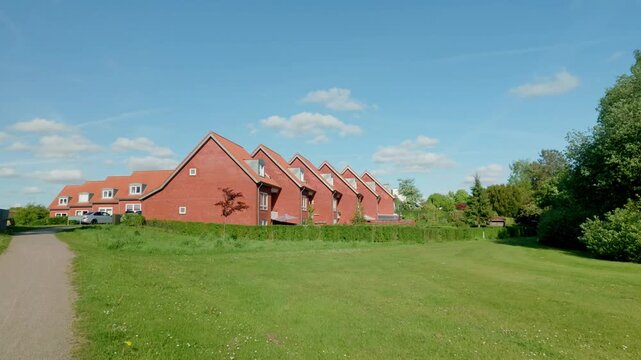 Row of traditional red brick houses in Billund, Denmark under clear blue sky.