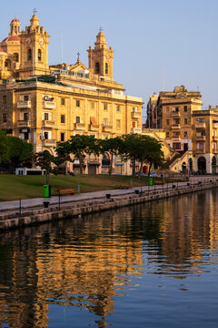 Historic architecture and waterfront reflection in Cospicua, Malta during golden hour