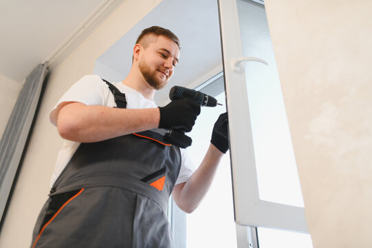 Worker installing window frame using electric drill