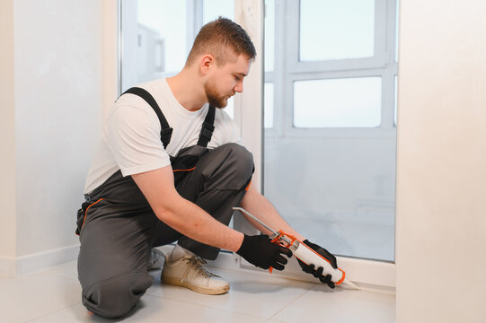 Worker applying caulk sealant during window renovation process