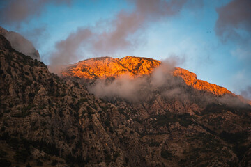 Naklejka premium Golden Mountain with Dramatic Sunset Clouds. Warm Sunset Light Over Rugged Cliffs.