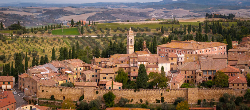 Italy San Quirico d'Orcia aerial panoramic view of Tuscany rolling hills valley background red roof tiles historic borgo townscape, classical Val d'Orcia landscape countryside