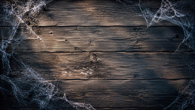 Spooky Halloween Background Featuring Realistic Cobwebs and Small Black Spiders on Dark Weathered Old Wooden Planks with Copy Space