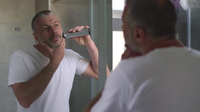 Man grooming in bathroom with electric shaver, 4k