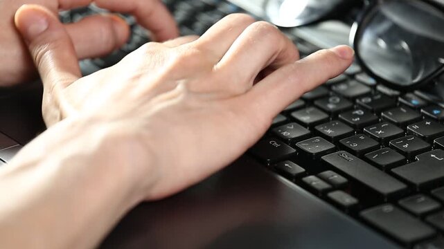 Business woman hands typing on a laptop with glasses on the keyboard. Online work, research on pc. Closeup workspace with person fingers