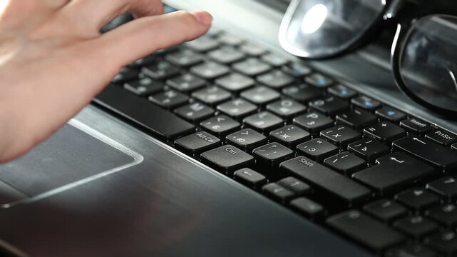 Business woman hands typing on a laptop with glasses on the keyboard. Online work, research on pc. Closeup workspace with person fingers