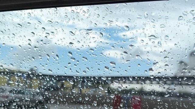 raindrops on glass against blue cloudy sky 
