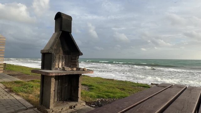 barbecue on a green lawn by the sea. Waves cloudy beach. Waves crashing . High quality 4k footage