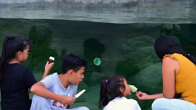 Latino family eating popsicles at the aquarium.