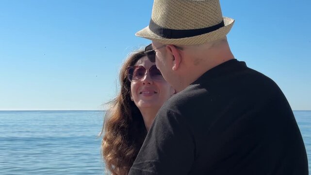Pareja madura lanzando piedras al mar y riendo