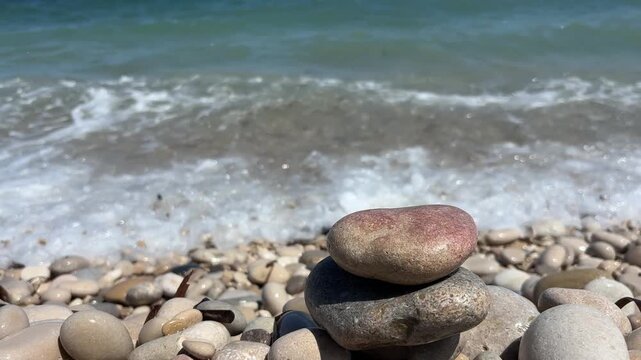 Mano apilando piedras en equilibrio frente al mar