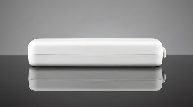 Closed white plastic thermometer storage case lying on reflective surface, medical equipment, healthcare supply, clinical tool