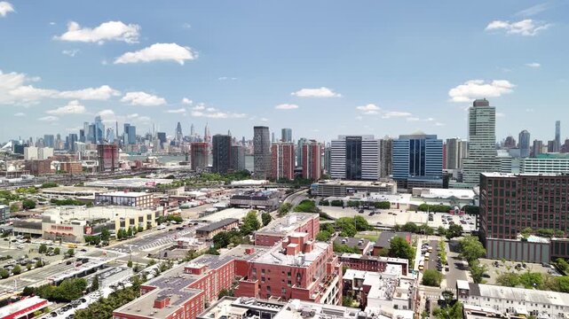 Expansive aerial view slowly revealing jersey city downtown and the new york city skyline with famous landmarks across the hudson river on a sunny day with blue sky