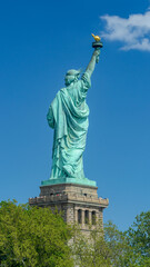 Fototapeta premium Statue of Liberty rear view against blue sky with cloud