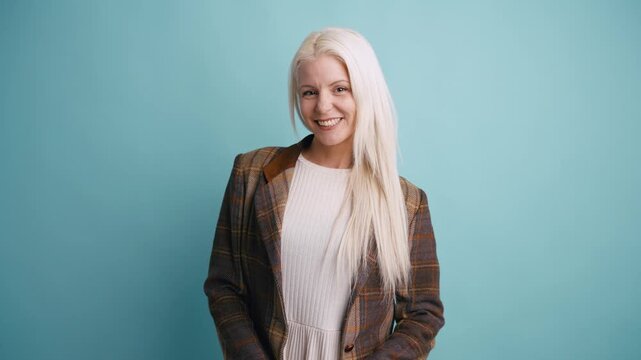 Cheerful beautiful woman with long platinum blonde hair smiling while posing in a studio. Portrait of a happy professional businesswoman