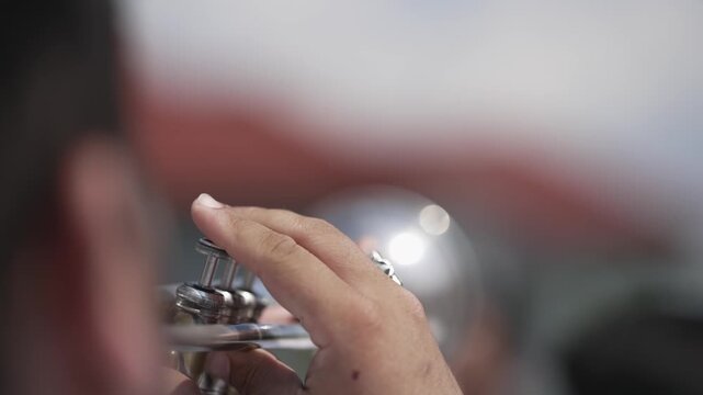 Detailed view of hands operating a trumpet mechanism, set in an outdoor wedding environment