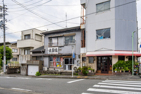 Retro street corner and old neighborhood storefronts in Nagoya Japan, including a small local shop and a small corner restaurant. An authentic, slow-paced slice of everyday Japanese urban life.
