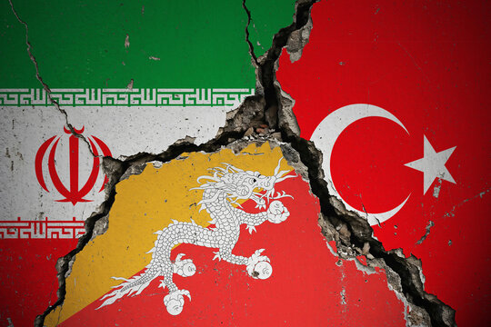 Cracked concrete wall with Iran, Turkey and Bhutan flags painted on it, symbolizing geopolitical tension and broken diplomatic relations.