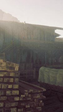 Wooden stacks sit in a construction area. Tools and equipment are scattered around. Early morning light filters through the space, creating a soft glow on the surfaces.