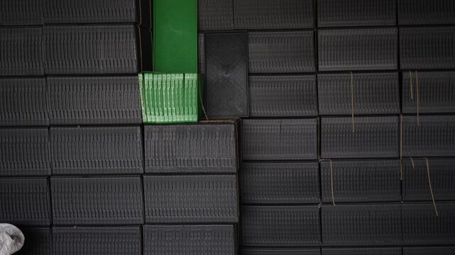 View of stacked black plastic crates in an industrial warehouse with a single green container Bogura, Rajshahi Division, Bangladesh.