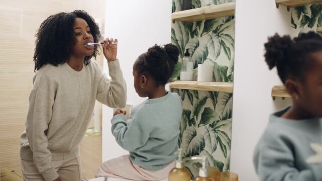 Loving mother teaching her young daughter about dental hygiene. Happy family enjoying their daily morning routine together in the bathroom