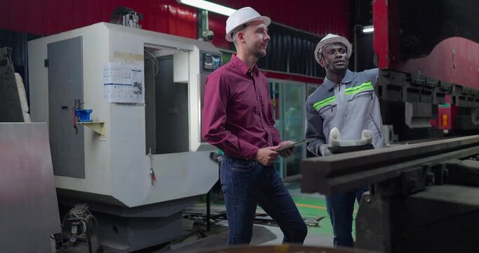 Sales Engineer Briefs Client on Machine Capabilities in Metal Workshop